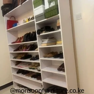 Tall white open shoe storage rack with multiple shelves, a wide main section and a narrow side column filled with footwear.