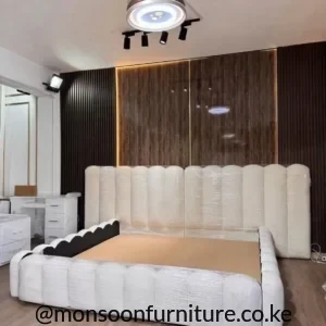 White upholstered bed with tall rounded vertical panel headboard and matching padded-look footboard in a modern bedroom.