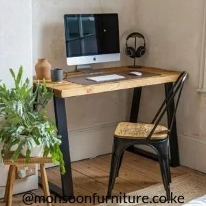 Wood-grain work desk with a warm brown rectangular top and angled black legs in a compact home-office setup