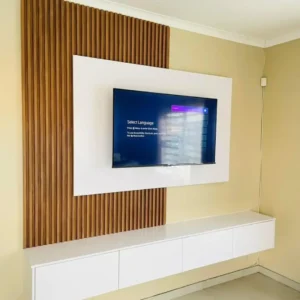 White floating TV wall unit with warm wood-look vertical slats and a long wall-mounted storage console in Kenya