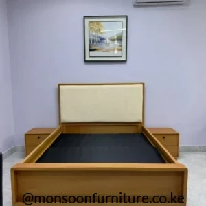Warm wood-tone bed frame with cream upholstered rectangular headboard and two matching bedside tables in a bright bedroom.