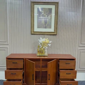 Wooden buffet table with six drawers, two open central cabinet doors and dark handles in a warm brown finish