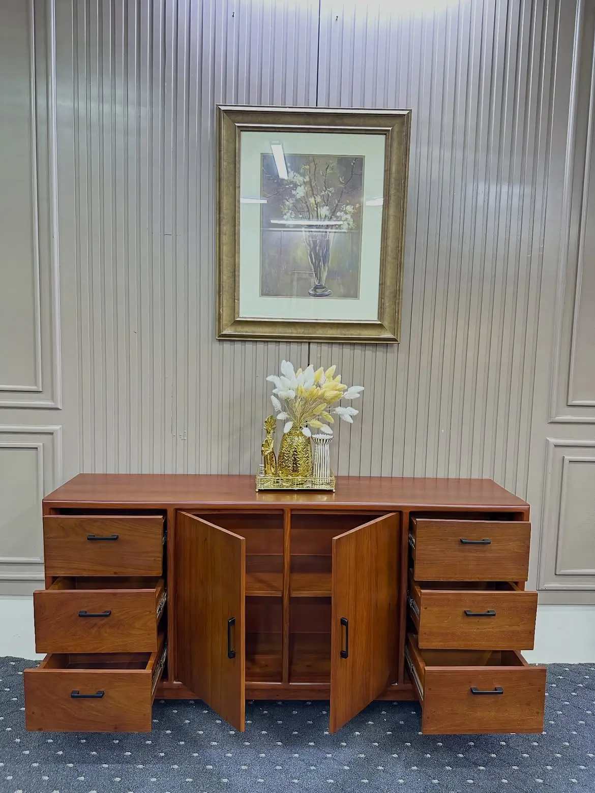 Wooden buffet table with six drawers, two open central cabinet doors and dark handles in a warm brown finish