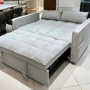 Light grey sofa bed opened flat with segmented cushioned surface and two loose back cushions