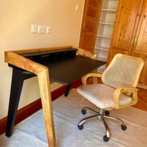 Black home office desk with natural wood-toned frame, raised rear shelf and open base in a furnished room