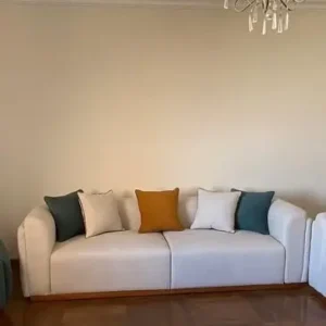 Cream 3 seater sofa with rounded arms, three seat cushions and contrasting scatter cushions in a living room