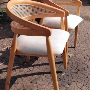 Cream upholstered accent chair with light wooden frame, curved arms and woven cane-style back