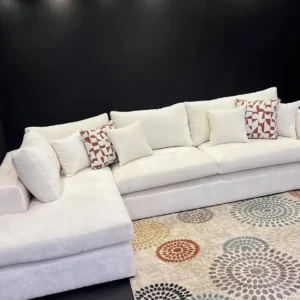Cream L-shape sofa with extended chaise, loose back cushions and patterned throw pillows