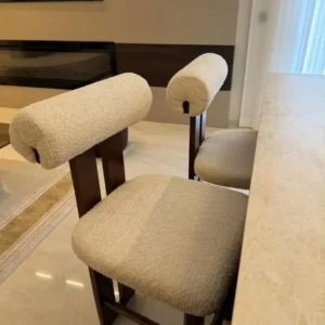 Cream upholstered bar stool with cylindrical backrest and dark wooden frame