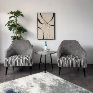 Two grey accent chairs with black, grey, cream and white striped seats beside a round table in a living room.