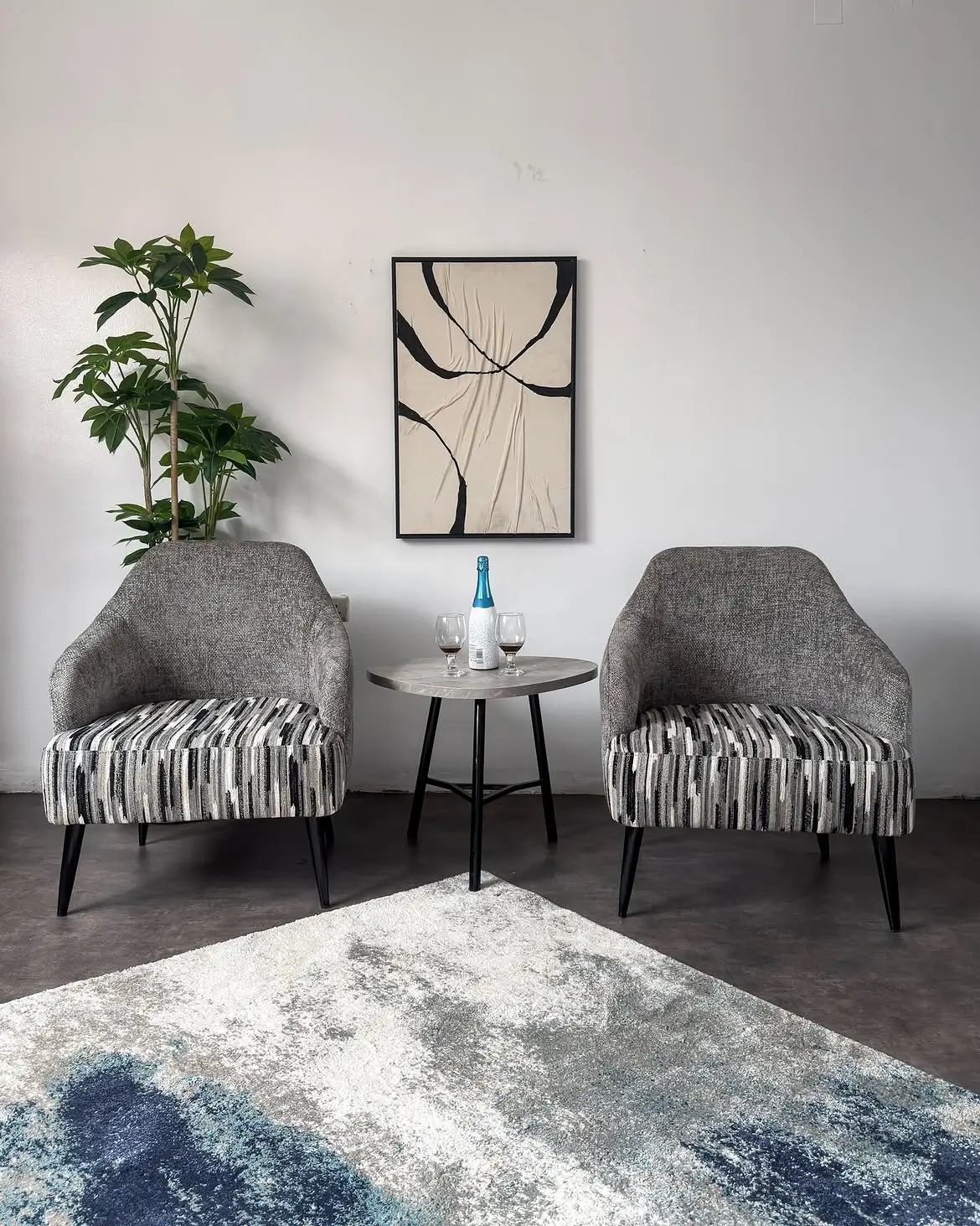 Two grey accent chairs with black, grey, cream and white striped seats beside a round table in a living room.