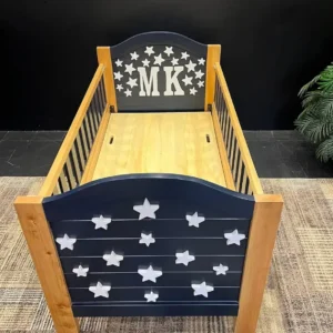 Dark blue kids bed with raised white stars, natural wood-tone posts and matching side rails