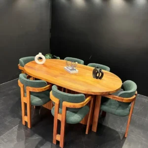 Oval wooden dining table with six green upholstered armchairs and central pedestal-style base