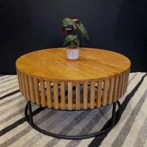 Round slatted wooden coffee table with warm brown top and black circular base in a living room setting