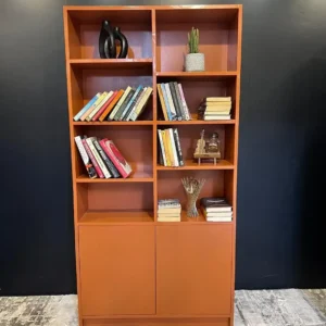 Rust orange office bookshelf with open shelves, books and two-door lower cabinet