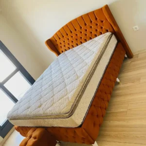 Rust-orange upholstered bed with winged button-tufted headboard
