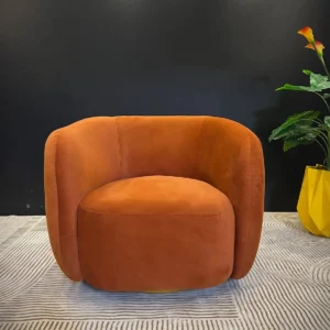 Monsoon Ambermere burnt-orange accent chair with rounded barrel back, integrated curved arms and wide cushioned seat.