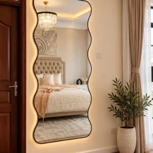 Tall black-framed wavy wall mirror with warm perimeter glow in a modern bedroom